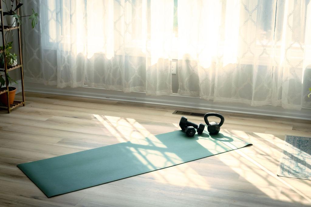 Rachael Williams on a workout mat at home with her dog, dumbbells beside her