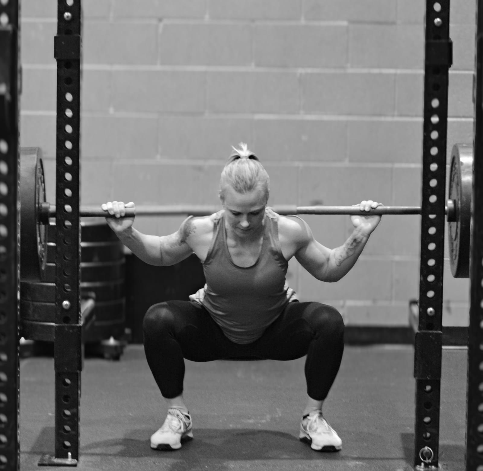 Rachael performing a barbell back squat in a squat rack
