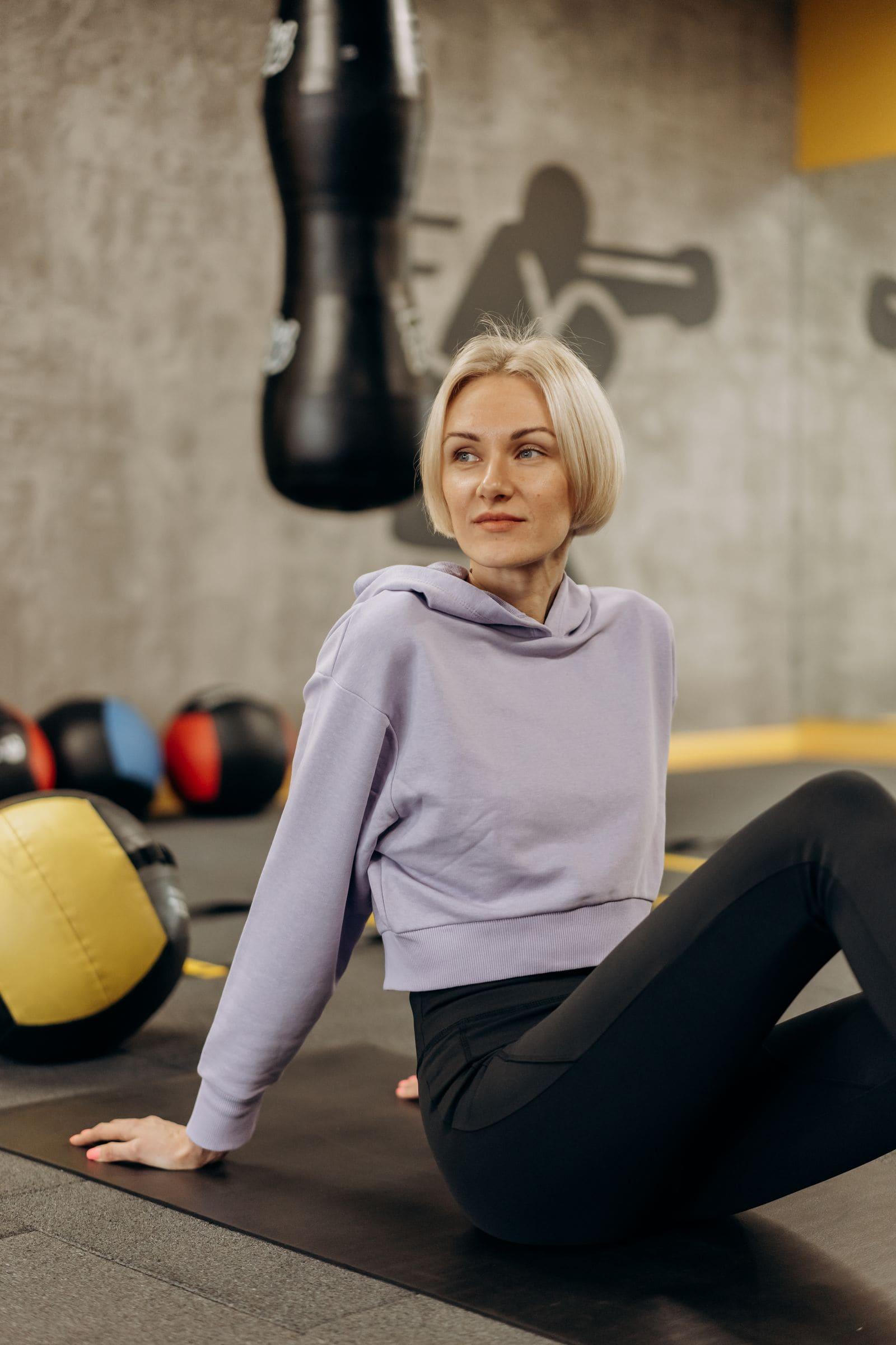 A blonde woman in a hoodie taking a moment at the gym